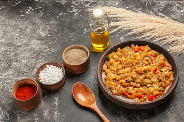 bottom view roasted eggplant salad in bowl wooden spoon oil different spices in small bowls on dark background