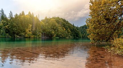 A beautiful lake among the mountains covered with autumn forest.