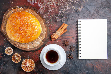 top view sweet baked bun with cup of tea on the dark background cake dough bread pie