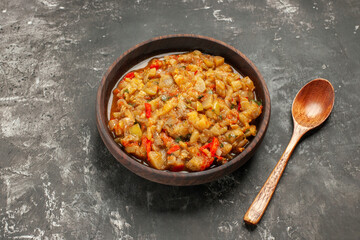 bottom view roasted eggplant salad in bowl wooden spoon on dark background