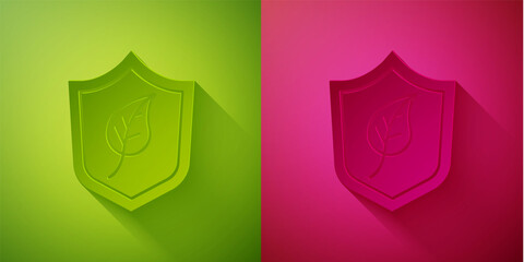 Paper cut Shield with leaf icon isolated on green and pink background. Eco-friendly security shield with leaf. Paper art style. Vector.