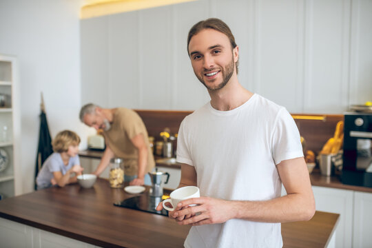 Young man in white tshirt standing in the kitchen and smiling