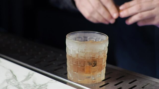 Young novice bartender trainee preparing a cocktail. Careless guy. Old fashion. Whiskey, scotch, brandy.