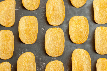 Top view of delicious homemade chips laid on gray background