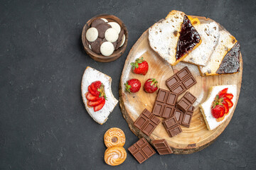 top view cake slices with chocolate bars and cookies on grey background biscuit fruit sweet