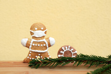 Gingerbread man with protective face mask, coronavirus and spruce twig. Concept in coronavirus (COVID-19) time, copy space for text