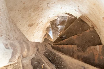 Fotobehang Gang Oude stenen wenteltrap in een kasteel of oude kerk. Onderaanzicht van de trap en smalle doorgang. Historische waarde en cultuur.  © Pokoman
