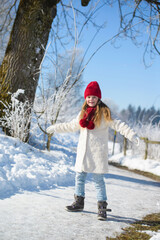 Happy little  girl walking in winter forest on a sunny day