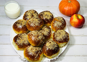 Sesame buns and a glass of milk. Fruit on a wooden table. Rustic breakfast. Late dinner in the village.