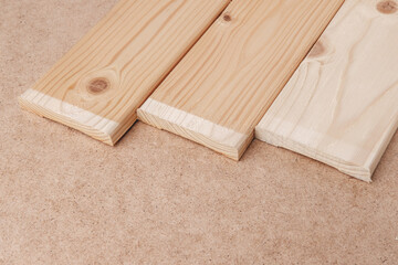 Wooden planks lie next to the shift. Furniture slats in different shades for assembling shelves with your own hands. The table is covered with pressed paper hardboard.