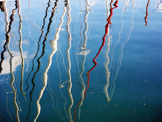 Colourful sailing boat masts reflected in the sea