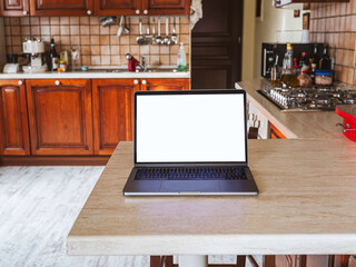 Working from home on the kitchen table with a neat workstation laid out with a laptop computer. Smart working