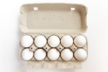 Cardboard egg box with chicken eggs on white background.