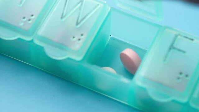 close up of putting pills and capsule in a pill box 