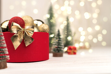 Red Christmas gift box with a gold bow and deer on the background of bokeh.