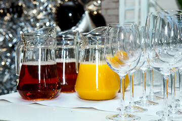 Glasses and glass decanters with orange and grape juice on the table.