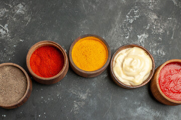 Obraz na płótnie Canvas Top view of set for sauces containing different spices mayonnaise and ketchup on gray background