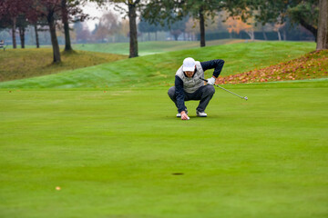 Obraz premium Golf player checking line for putting golf ball on green grass