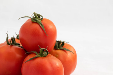 Vitamins And Minerals Rich Red And Orange Colored Desi Indian Local Tomatoes Known As Tamatar With Green Flower Leaves On The Top Isolated On White Background With Blank Copy Space For Custom Text