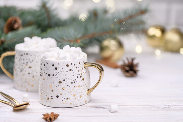 White cup of cappuccino or cocoa with christmas tree on the buckground of gold bokeh, New Year drink