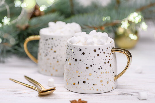 White cup of cappuccino or cocoa with christmas tree on the buckground of gold bokeh, New Year drink