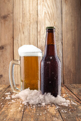 Cerveza en taberna bien fría con hielo en mesa de madera con baso frío y espuma
