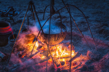 Selective focus on boiling cauldron with mysterious decoction on a campfire at night witch sabbath....