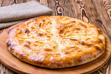 Ossetian pie with cheese and potatoes on wooden table
