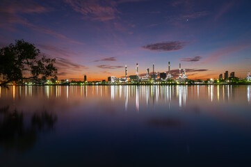Fototapeta premium oil refinery plant chemical factory and power plant with many storage tanks and pipelines beside river at sunrise.