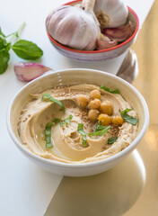 Hummus with Garlic and basil isolated on golden and beige background