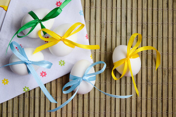 Easter eggs with colorful satin ribbon bows. Spring holiday. Easter photo background. Easter holiday eggs with ribbons.