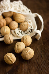 beautiful whole walnuts scattered on a wooden table from a string bag