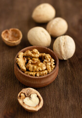 many whole walnuts on a board next to chopped walnuts and walnut kernels on a wooden background