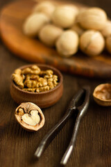 Fototapeta na wymiar walnuts and nutcracker, whole nuts, walnut shells and kernels on wooden background