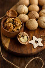 Fototapeta na wymiar many whole walnuts on a board next to chopped walnuts and walnut kernels on a wooden background