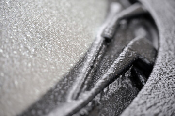Shallow depth of field with detail of a frozen car windscreen and wipers after freezing rain phenomenon