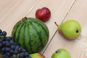 Watermelon, grapes, pear and apple on the background of the boards.