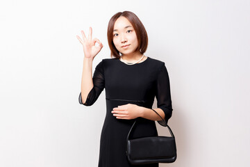 喪服を着たOKのポーズをする女性