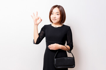 喪服を着たOKのポーズをする女性