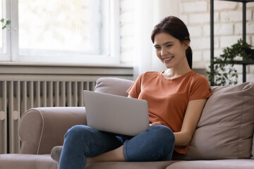 Obraz premium Stay at home. Smiling confident young woman remote worker spending time indoors at quarantine period doing job on pc. Female student communicating with friend by video call app on laptop study online