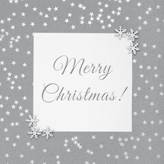 Obraz na płótnie Canvas Christmas greeting card with silver snowflakes on grey background. Postcard with the text Merry Christmas. Happy New Year. Winter concept.