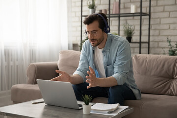 E-learning. Confident young man trainer tutor working at home providing video conference using pc...