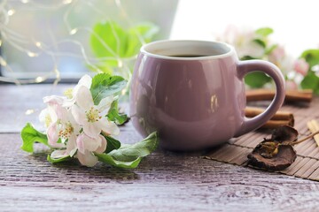 Fototapeta na wymiar Cup of coffee with spices, flowering branches on a wooden table against the background of a window, spring, the concept of home comfort, morning