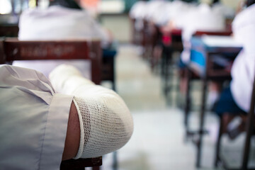 injured Students taking exam with stress in school classroom