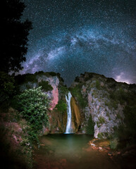 Night landscape, A waterfall flows down the mountain to a small lake, while the milky way illuminates the image. A beautiful waterfall in Spain, the stars illuminate the lake.