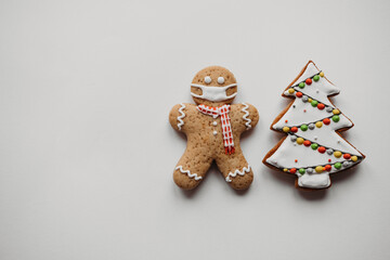 Happy New Year's set of cookies, gingerbread man in face mask, xmas tree, from ginger biscuits glazed sugar decoration on white background, minimal seasonal pandemic winter holiday banner