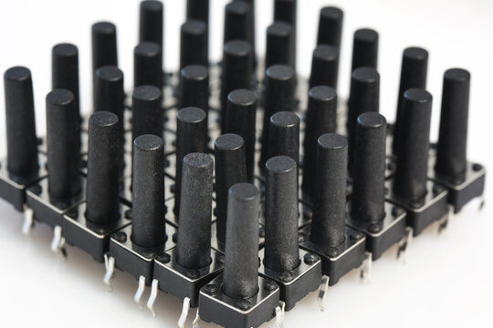 Abstract background of black plastic microswitch on white background. Electronic component spare part and industry concept. Selective focus, shallow depth of field.