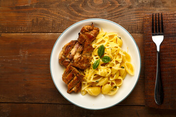 A plate of pasta in a creamy sauce with cheese and chicken on the table next to the fork. copy space.