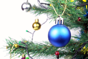 Christmas blue ball on an artificial white Christmas tree, white background, selective focus, bokeh.