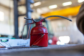 Close-up image of old red color metal oiler in indoor workshop